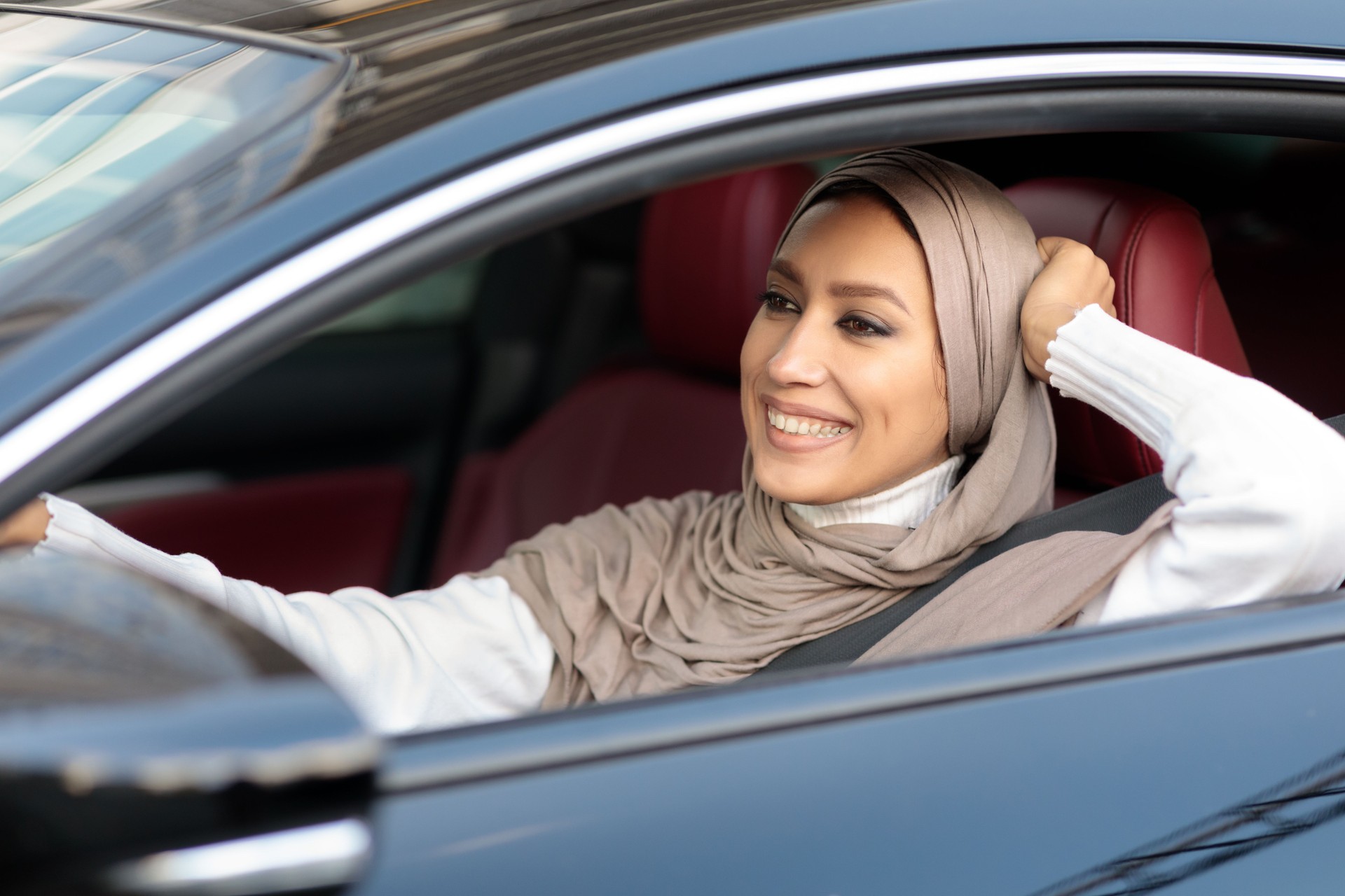 Mulher muçulmana alegre dirigindo seu carro novo