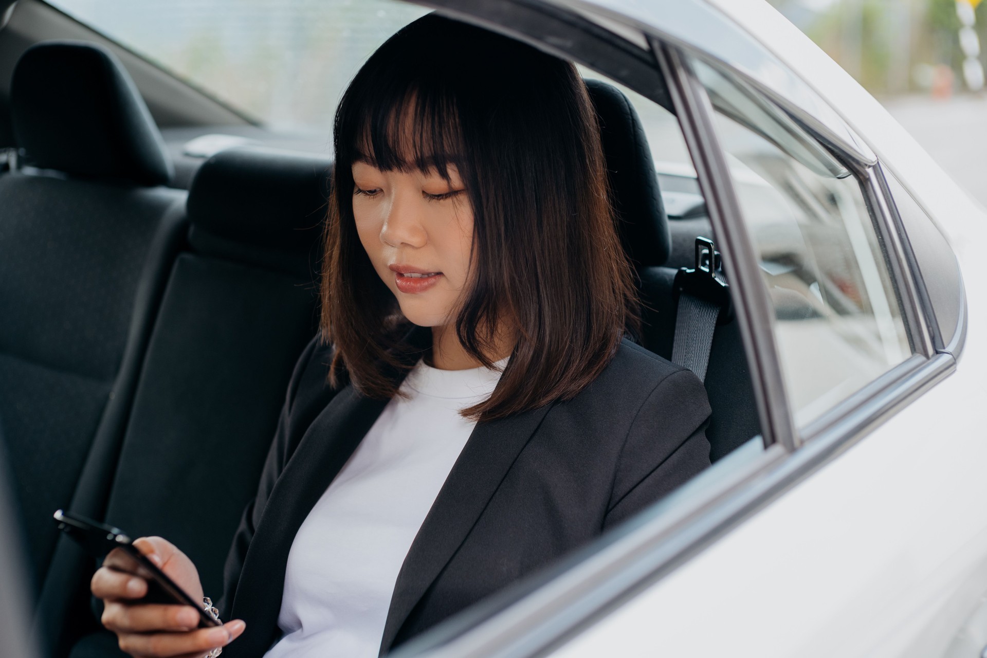 Jovem empresária asiática usando smartphone no carro