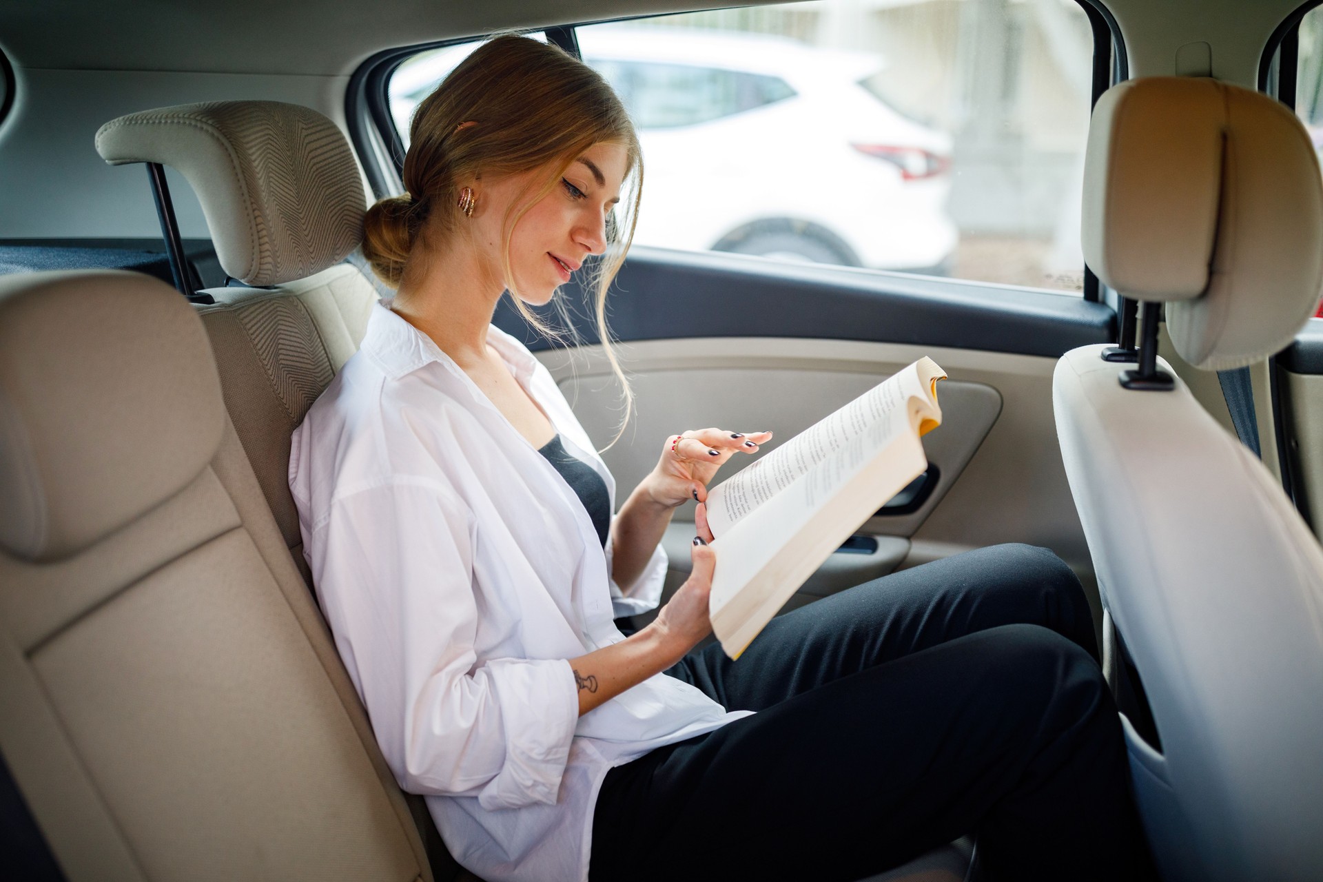 Linda garota lendo livro no banco de trás do carro