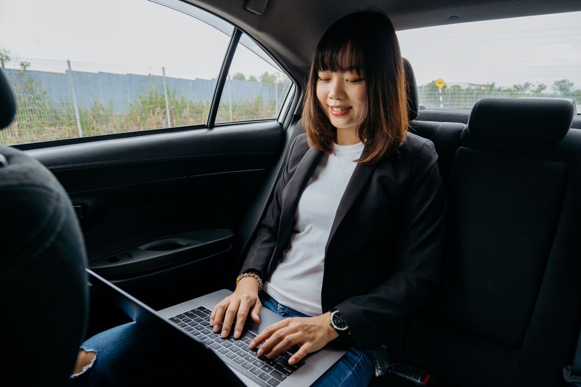 Jovem empresária asiática usando laptop em táxi